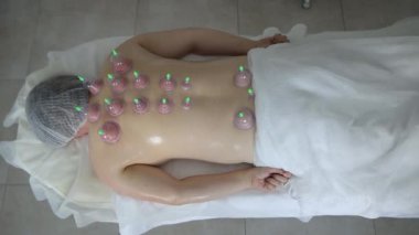 Klinikte sırtında elektrikli süpürgeyle masaj yatağında uzanan rahat bir kadın. Yüksek kalite 4k görüntü