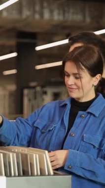 Dikey video genç çift seramik fayansları bir inşaat süpermarketinden seçiyor. Yeni bir ev için yapı malzemesi seçimi