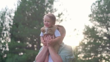 Dışarıda çocuklarla bağ kuran, omuzlarında bir kız taşıyan, bebeği kucağında tutan ve neşeli bağlarını yakalayan bir adamın yürek ısıtan bir videosu.