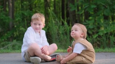 İki genç çocuk yumuşak zeminde oturuyor ve birbirleriyle canlı sohbetler yapıyorlar, birlikte vakit geçiriyorlar.