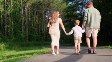 Ormanda yürüyen, el ele tutuşan, huzurlu bir yolda yemyeşil bir ailenin yürek ısıtan bir videosu.