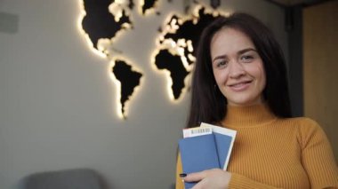 Heyecanlı genç bir kadın, kitap, pasaport, biletler ve maceraya hazır olduğunu gösteren bir dünya seyahatine hazırlanıyor.