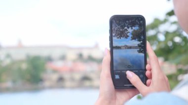 Bir kadının fotoğraf çektiği bir akıllı telefon ekranının yakın çekimi. Bir kadın eli, bir şehir panoramasının akıllı telefonuyla fotoğraf çekiyor. Turizm. Telefondaki fotoğraf.