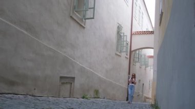 Arka planda bir kadın Avrupa 'nın eski dar bir sokağında yürüyor. Prag 'ın tarihi yerlerinde bir yürüyüş.