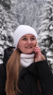 Sakin, karlı bir manzarada, şık beyaz şapkalı ve eşarplı bir kadın bir telefon görüşmesi yapar, sıcaklığı ve bağlantıyı yakalar.