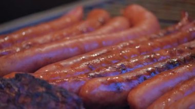 BBC ızgarasında ızgara sosis yapan metal dilleri kapatın. Yüksek kalite 4k görüntü