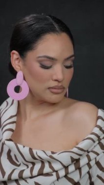 Küpeli, güzel bir esmer ve omuzları çıplak bir şekilde video çekimi için poz veriyor. Yüksek kalite 4k görüntü