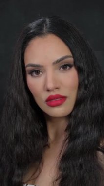 Siyah saçlı ve kırmızı rujlu bir kız kameranın önünde poz veriyor. Yüksek kalite 4k görüntü