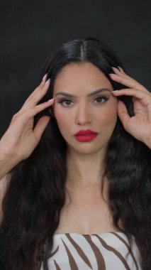 Güzel bir kadın kendi siyah saçlarını okşuyor ve kameraya bakıyor. Yüksek kalite 4k görüntü