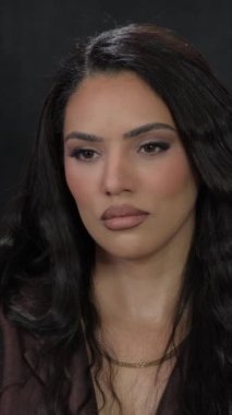 Siyah dalgalı saçlı, kahverengi gözlü ve kahverengi rujlu bir kız fotoğraf çekimi için poz veriyor. Yüksek kalite 4k görüntü