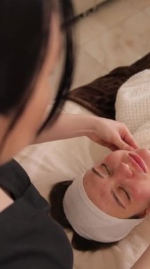 Dikey videoda bir kadın spa 'da masaj yaptırıyor ve sakin bir atmosfer yaratıyor. Özbakım ve spa hizmetlerini desteklemek için ideal