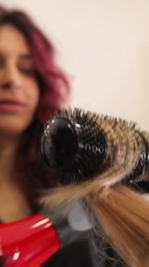 Dikey video, kuaförde saçını kurutan genç bir kadın. - Evet. Yüksek kalite 4k görüntü