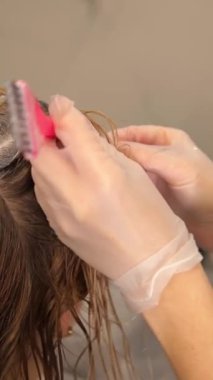 Dikey video, kuaför müşterisinin saçlarını bir güzellik salonunda beyaza boyuyor. Yüksek kalite 4k görüntü