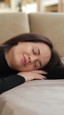 Dikey video, mobilya mağazası, bir kadın kanepede huzur içinde uyuyor, rahatlık ve rahatlık sergiliyor.
