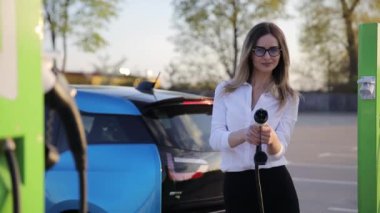 Benzin istasyonundaki kadın. Beyaz tişörtlü ve gözlüklü güzel bayan arabanın yanında. Yüksek kalite 4k görüntü