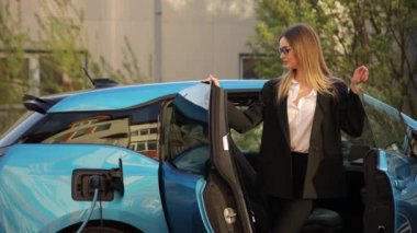 Elektrikli arabadan inen, sürdürülebilir ulaşım ve çevre dostu uygulamalar sergileyen, takım elbiseli profesyonel bir kadın.