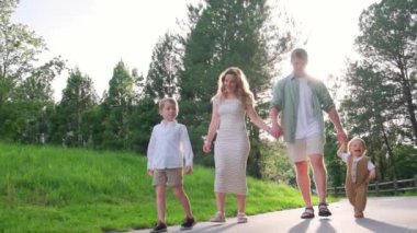 Yürek ısıtan bir sahne, bir aileyi güzel, ağaçlı bir parkta el ele yürürken gösteriyor, neşe, bağ ve birlikteliği yansıtıyor.