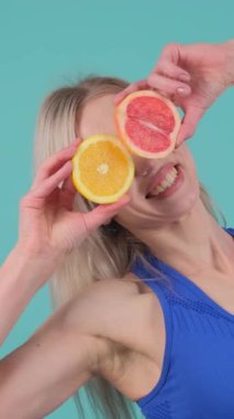 Bu canlı videoda, bir kadın limon, portakal ve greyfurttan zevk almak için ilginç bir yaklaşım sergileyerek turunçgil dilimlerini eğlenceli bir göz kapağı olarak kullanır.