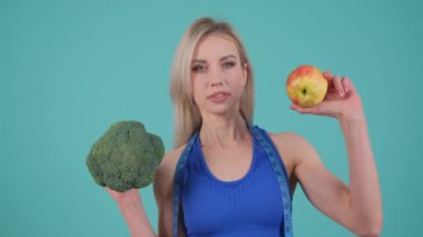 Bu videoda, bir kadın brokoli ve elma tutarak sağlıklı bir yaşam tarzını ön plana çıkarıyor, günlük yemekler için besleyici yeme alışkanlıklarını teşvik ediyor.