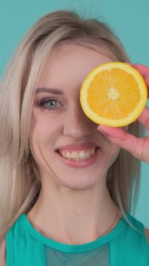 Bu eğlenceli videoda, bir kadın gözünün önünde portakal ve limon dilimleri kullanıyor. Canlı renkler eğlence ve yaratıcılığı vurguluyor.