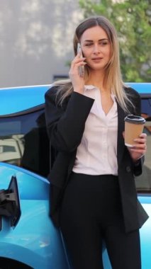 Dikey videolu kadın mavi elektrikli bir arabanın yanında durup telefonla konuşuyor. Sahne onun birden fazla iş yaptığını gösteriyor. Bir telefon görüşmesi ve çevre dostu ulaşım aracı.