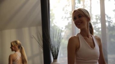 Güneş ışığı penceresinin arkasında duran güzel, gülümseyen bir sarışının portresi. Oturma odasındaki sportif kadın. Güzel insanlar. Mutluluk kavramı