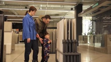 Genç ve mutlu bir çift ve küçük oğulları evleri için fayans seçiyorlar. Bir baba oğullarının elini tutar. Yüksek kalite 4k görüntü