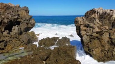 Dalgaların uçurumlara çarptığı kayalık bir kıyı şeridini deneyimleyin. Geniş okyanus manzaralı ve doğası olan dingin açıkları ortaya çıkarır.
