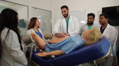 Kadın doğum uzmanı-jinekolog öğretmenleri ve hamile bir mankenin yanında öğrenciler. Jinekoloji. Yüksek kalite 4k görüntü
