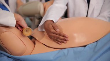 Öğretmen tıp öğrencilerine mankenli hamile bir kadının karnını gösteriyor. Jinekoloji. Yüksek kalite 4k görüntü