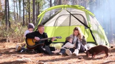 Ormanda kamp yapan bir aile. Çadırın etrafında toplanırlar, mutlu hikâyeler paylaşırlar, gülerler ve müzik çalarlar..