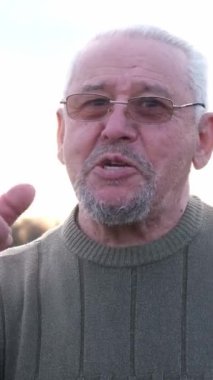 Bu video, yeşil kazak giyen, gözlüklü sakallı bir adamı, tutkuyla şarkı söylerken ve etkileşirken, sıcaklık ve coşku gösterirken gösteriyor.
