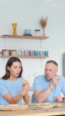 Bir erkek ve bir kadın bir masada oturup, keyifli bir şekilde sohbet ederken lezzetli pizzalarının tadını çıkarıyorlar.