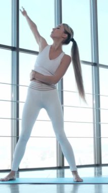 Bir kadın doğal ışıkla aydınlatılmış minder üzerinde yoga yapıyor. Bu ortam barışı ve farkındalığı teşvik ediyor, güç ve rahatlama pozları veriyor.