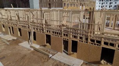 Bu video yapım aşamasındaki büyük ahşap bir binanın hava görüntüsünü gösteriyor, ahşap çerçevelerin montajını ve faaliyetlerin boyutunu vurguluyor.