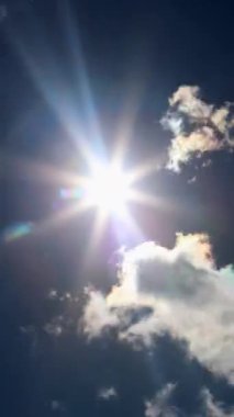 Güneş ışığı tüylü bulutları delip geçiyor, canlı mavi gökyüzüne sıcaklık saçıyor. Bu sakin sahne, doğanın güzelliğine umut veriyor ve onu davet ediyor.
