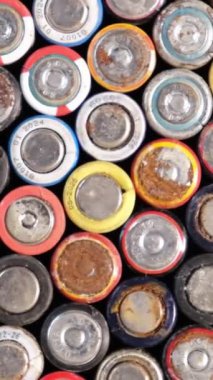 Bu video, eski bataryaları bir masanın üzerine istiflenmiş, yıpranmış görünüm ile geometrik hizalama, enerji tüketimi ve elektronik atık temaları çağrıştıran