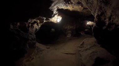 Lambalarla aydınlatılmış bir yeraltı mağarasında ateş etmek. Dağ sırasındaki taş bir mağarayı keşfetmek. Doğal harikalar. Yeraltı turizmi