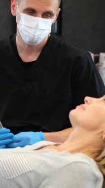 Modern bir diş kliniğinde dişçi, dişçiye ağız sağlığı için dişlerini muayene eder. Video düzenli kontrollerin önemini vurgular