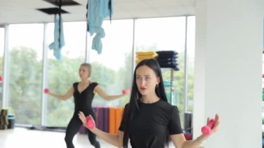 Spor salonundaki genç kadınlar dambıllarla çalışıyor. Spor salonu. Yüksek kalite 4k görüntü