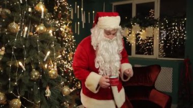 Noel Baba gibi giyinmiş bir adam güzel süslenmiş bir Noel ağacının önünde dans eder, bayramın neşesini ve neşesini yakalar.