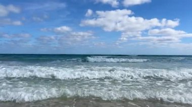 Pofuduk bulutlarla aydınlık mavi bir gökyüzünün altında dingin bir sahil manzarası beliriyor. Dalgaların ritmik sesi rahatlamak için resim gibi bir ortam yaratır.