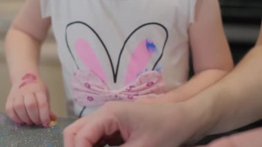 Anne ve kızı evde bir fırçayla Paskalya yumurtalarını boyuyor, bayram için hazırlanıyorlar..