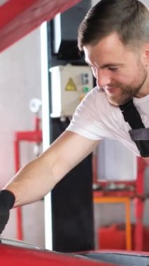 Samimi bir garajda, yetenekli bir tamirci canlı kırmızı bir araba üzerinde çalışır, motoru kontrol eder ve kendini adamış ve neşeyle bakım yapar.