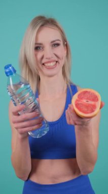Bir kadın, su ve greyfurtla ferahlatıcı bir anın tadını çıkarır, sağlıklı yaşam ve suyu somutlaştırır, refahı ve kendine bakımı vurgular.