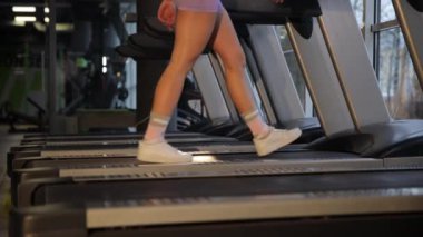 Koşu bandında yürümek, modern bir spor salonunda forma olan bağlılığını göstermek..