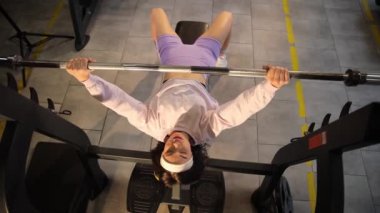 Kararlı ve kasıtlı bir kadın ağırlık kaldırır, modern bir spor salonunda etkileyici bir güç gösterir..