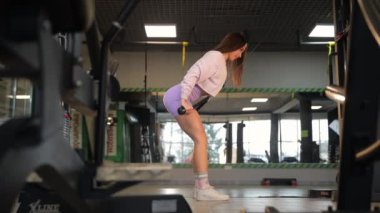 Odaklanmış bir birey, modern bir spor salonunda ağırlık kaldırırken ve güçlü bir eğitim alırken görülüyor.