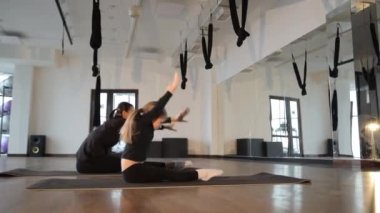 Stüdyoda yoga pratiği yapan anne ve kız, egzersiz yaparken etkileyici esneklik ve denge gösteriyorlar..