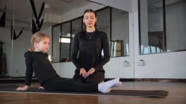 Bir çocuk, huzur verici bir sağlık stüdyosunda tecrübeli bir eğitmenin rehberliğinde hevesle yoga yapıyor..